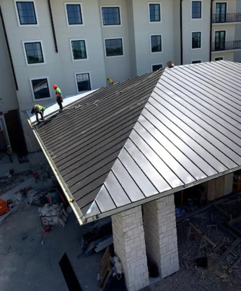 Crew installing standing seam metal roof panels on a commercial project in Plain City